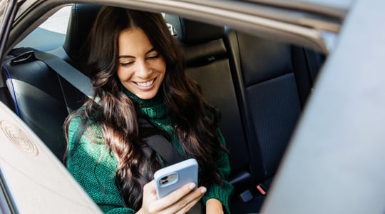 onpoint digital banking-young woman sitting in a car depositing money and reviewing digital banking accounts