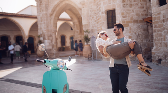 couple traveling in europe standing near a moped