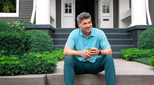 Man-drinking-coffee-sitting-on-steps-of-home