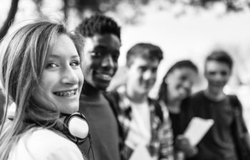 Teenage girl wearing headphones smiles with her friends