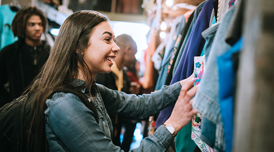 A smiling group of young adults have fun shopping for retro and vintage clothing styles.