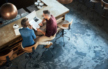 Two business people working on paperwork and laptop at their local coffee shop
