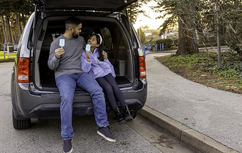 man-sitting-with-daughter-in-the-back-of-a-car-eating-ice-cream