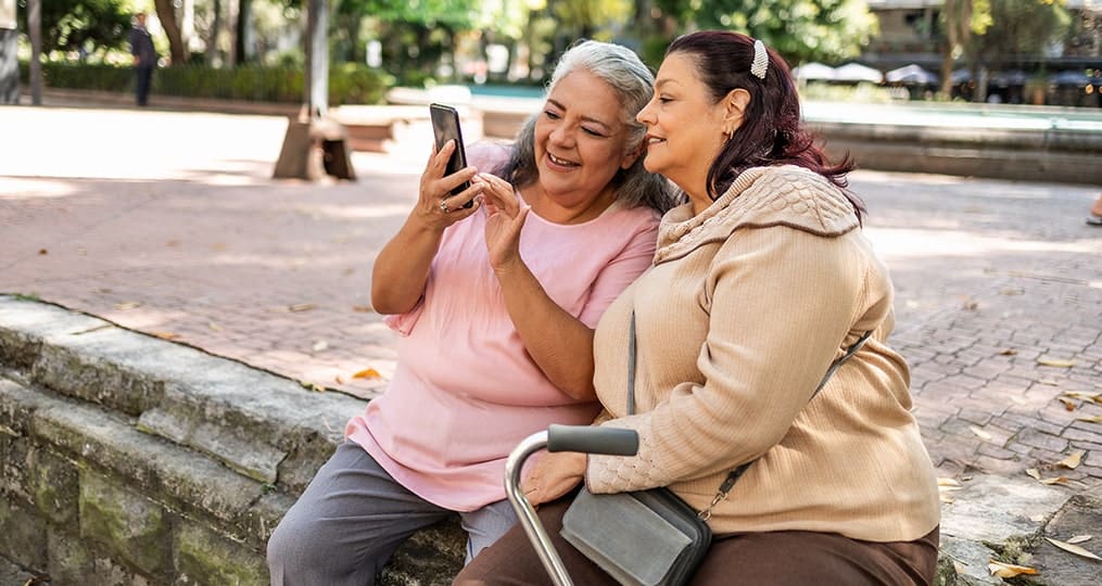 two-senior-hispanic-women-using-mobile-phone