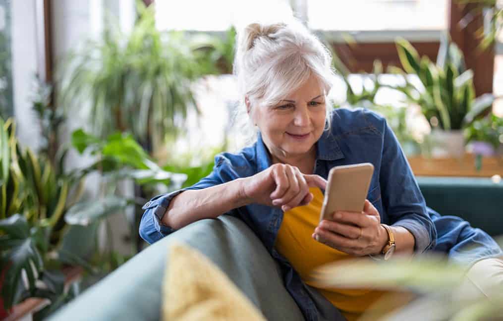middle aged woman looking at phone sitting on couch onpoint community credit union security cybersecurity