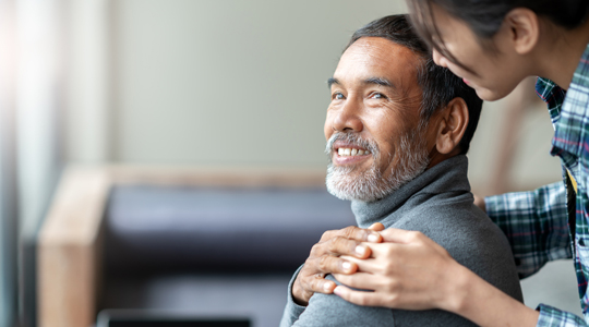 Smiling happy older asian father with stylish short beard touching daughter's hand on shoulder