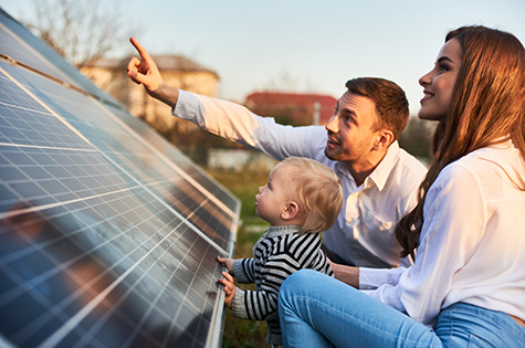 Young woman with a kid and a man in the sun rays look at the solar panels.