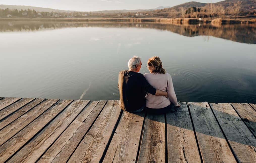 Older couple sitting on dock looking out at lake onpoint summer skip pay 2025