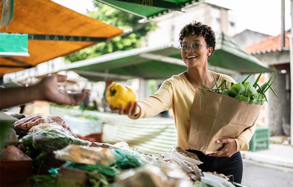 woman shopping at local farmers market buying yellow pepper onpoint credit union support local