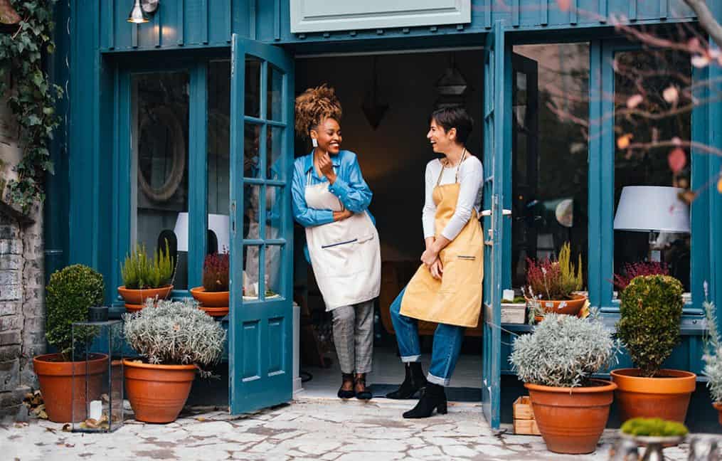 two business owners out side of store front women talking and smiling support local onpoint
