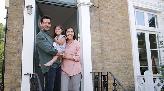 family stands at the doorstep of their new home