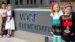 four kids in front of school sign
