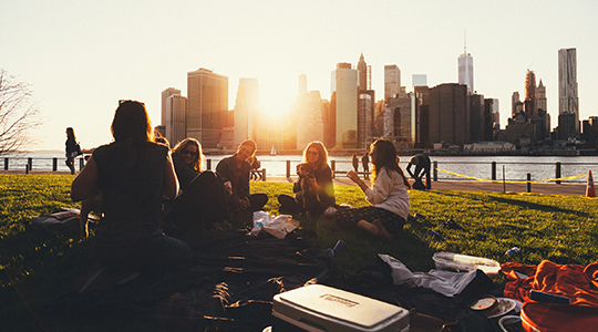 Group of students gathering at a riverside park at dusk, sunset.