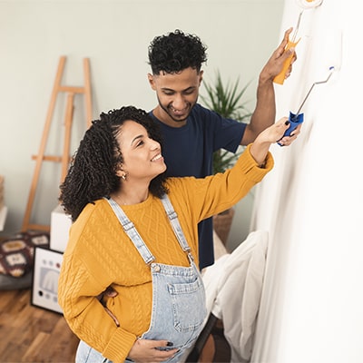 pregnant couple painting a room together