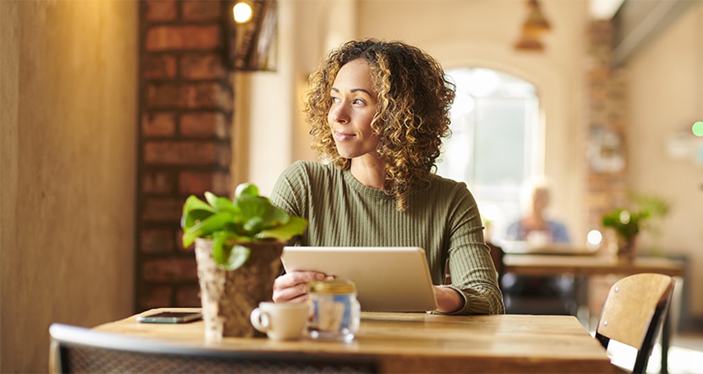 woman looking outside with tablet in hand