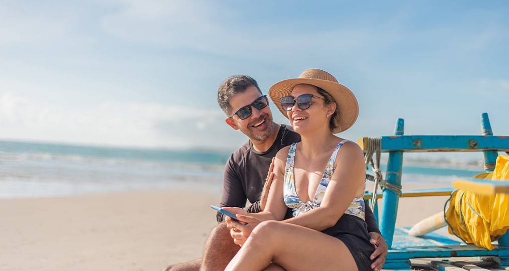 tourist couple using smartphone on the beach