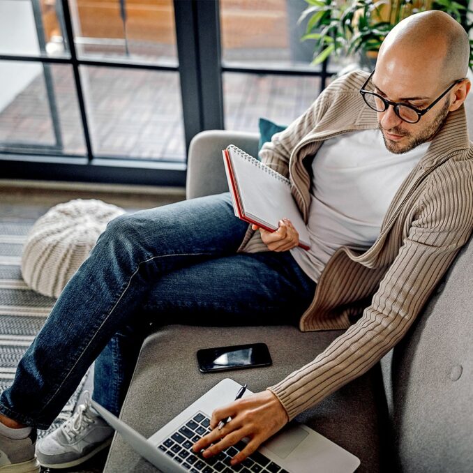 3 healthy financial habits to start now-man looking up finances on laptop and writing down expenses in notebook