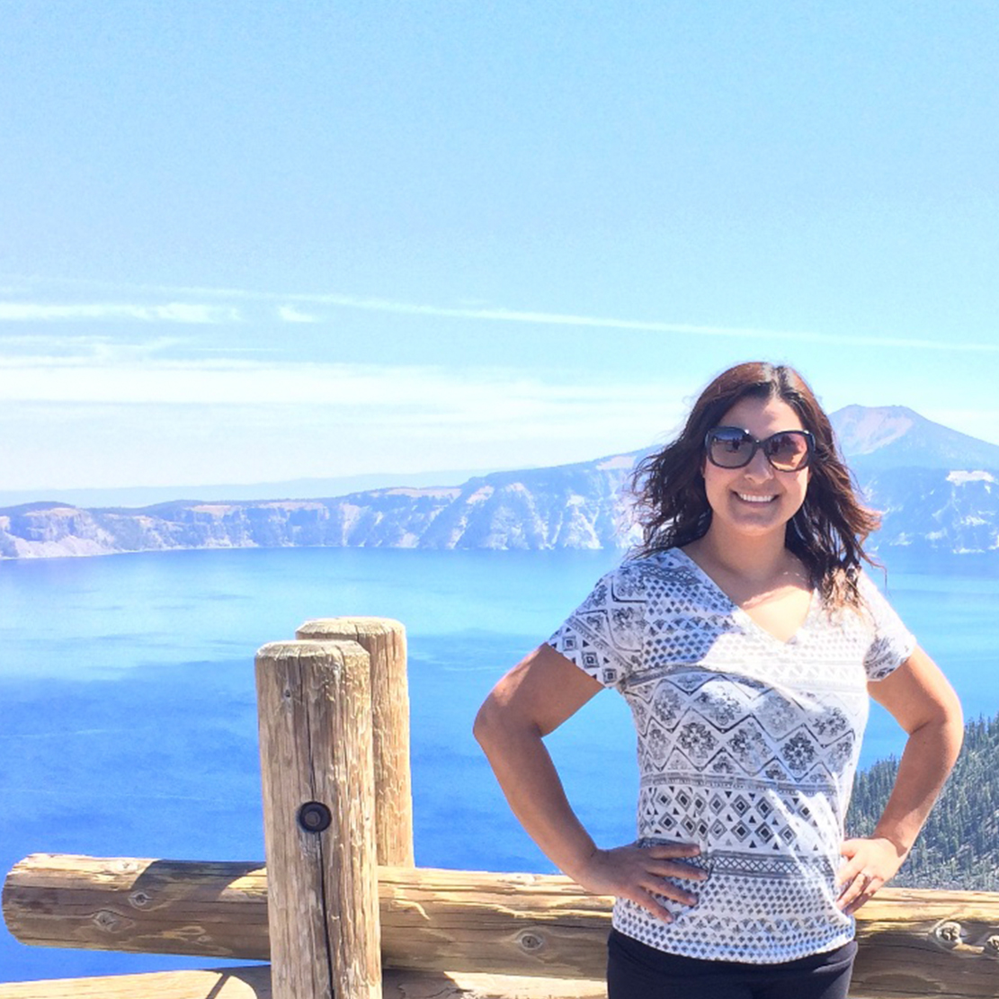 Spotlight Interview with Marlen Mendoza-Marlen posing in front of a scenic mountain and lake view in the pacific northwest crater lake