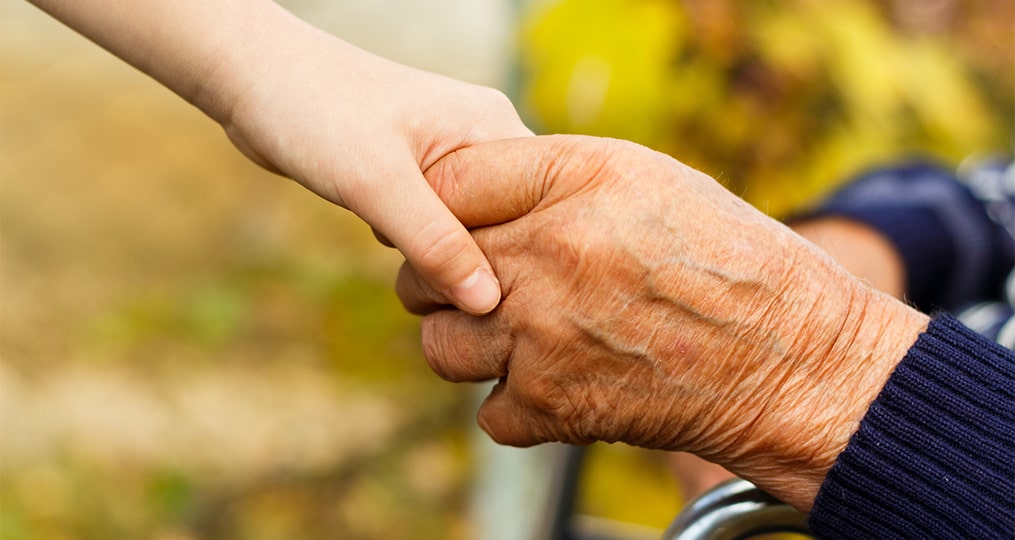 close up of an elder holding hands with young child