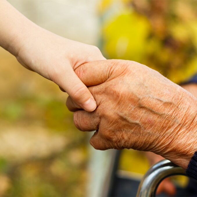 close up of an elder holding hands with young child