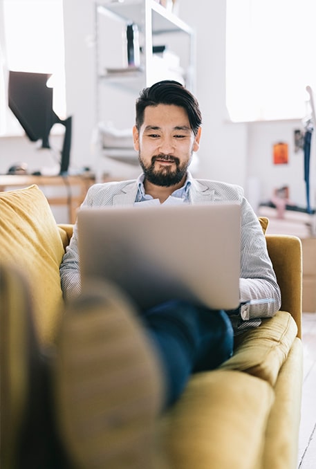 Traits of a Great Financial Advisor-pleased japanese man researching advisors from the couch