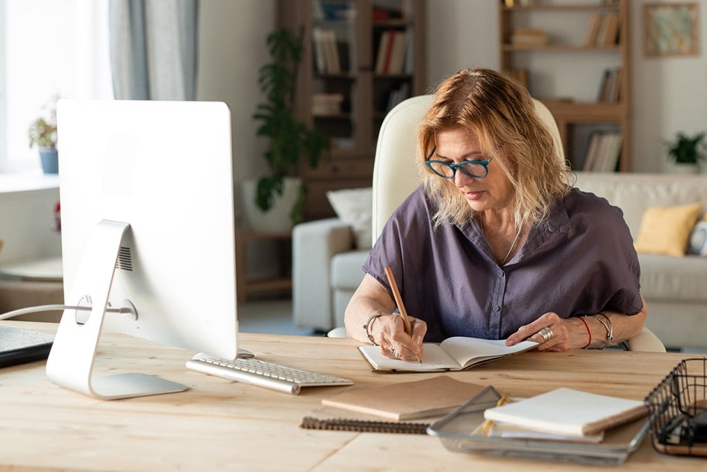 What Should You Ask a Financial Advisor-mature woman taking notes at her desk