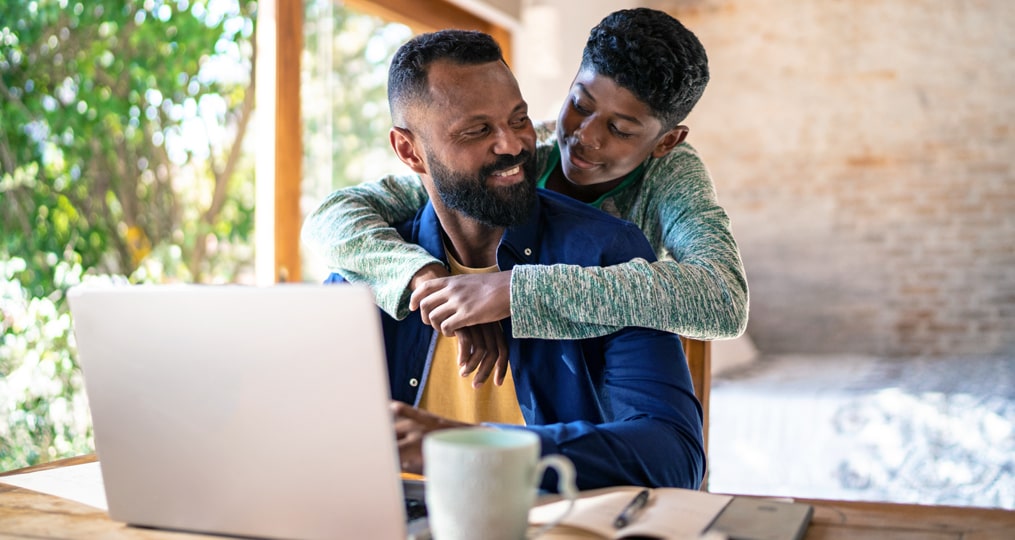 father and son sitting at the computer reviewing financial education materials together