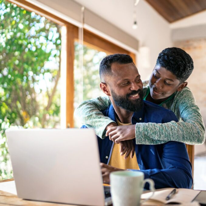 father and son sitting at the computer reviewing financial education materials together
