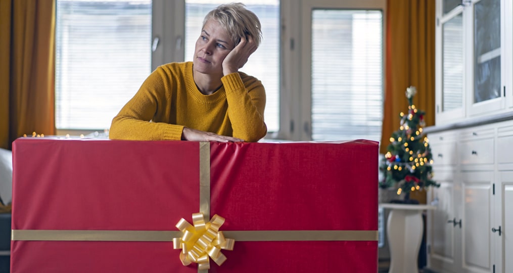 how to avoid holiday shopping scams-woman with large gift in her living room