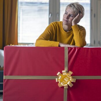 how to avoid holiday shopping scams-woman with large gift in her living room