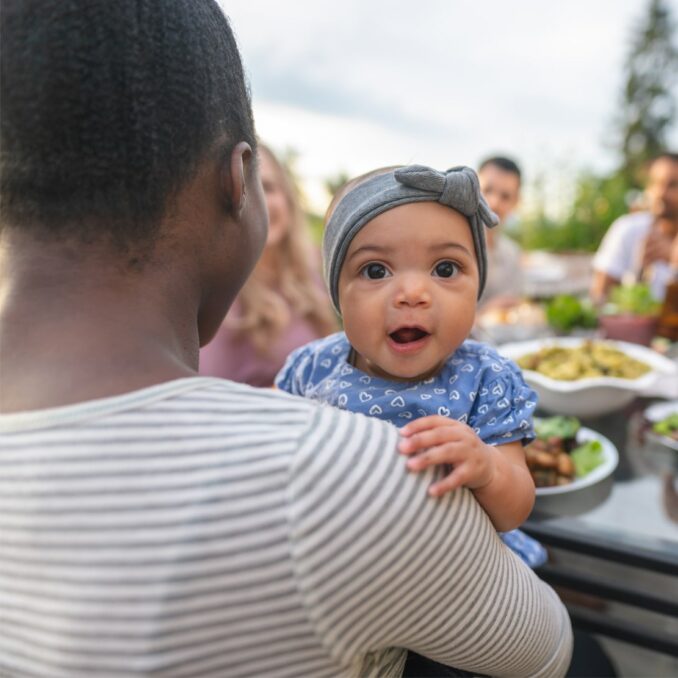 lending discrimination series part 2-new mother sitting outside during and gathering of family and friends