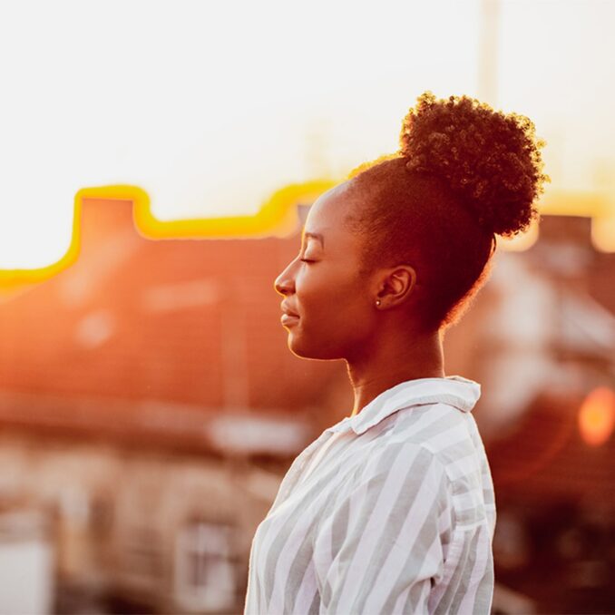 black woman closing her eyes in the sunset