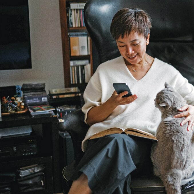 protecting your social security payout-woman sitting in an office chair petting her cat and using her phone