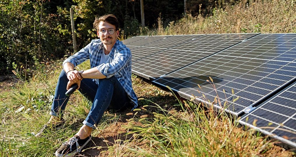 quick facts about the bright future of solar energy-man sitting next to solar panels