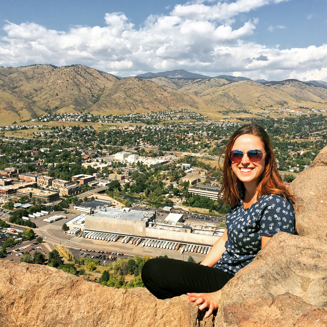 Francesca sitting on a hillside with a great view of a small town