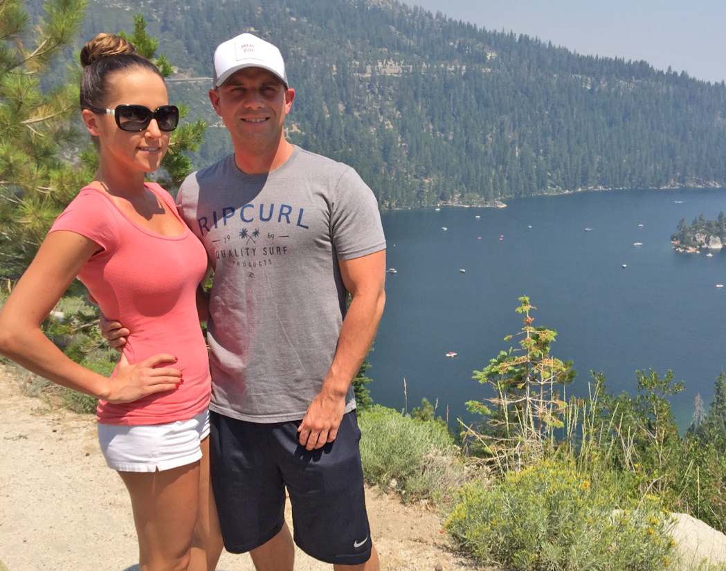 Katie and her husband on a hike overlooking a large lake