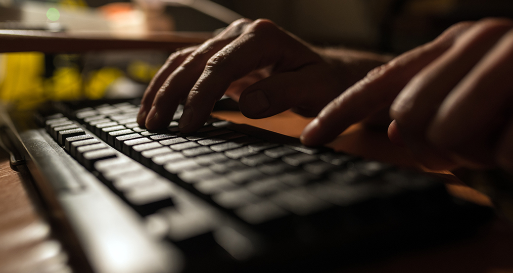 Understanding the Illegal Market for Personal Information_dark photo of hands typing on a keyboard