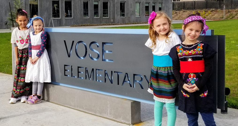 students outside of vose elementary school standing near the school sign