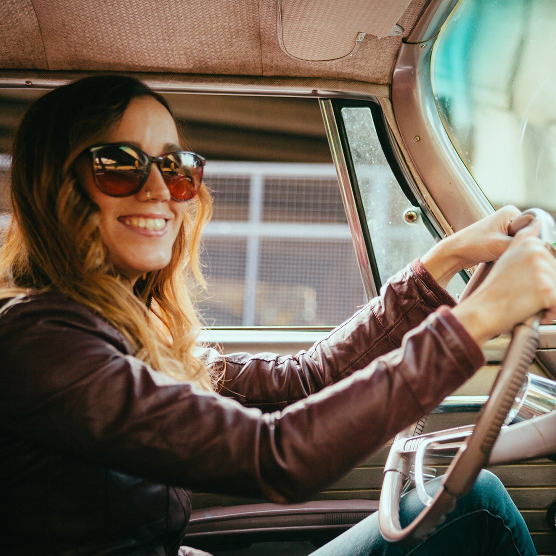 trendy woman sitting behind the wheel of a classic car