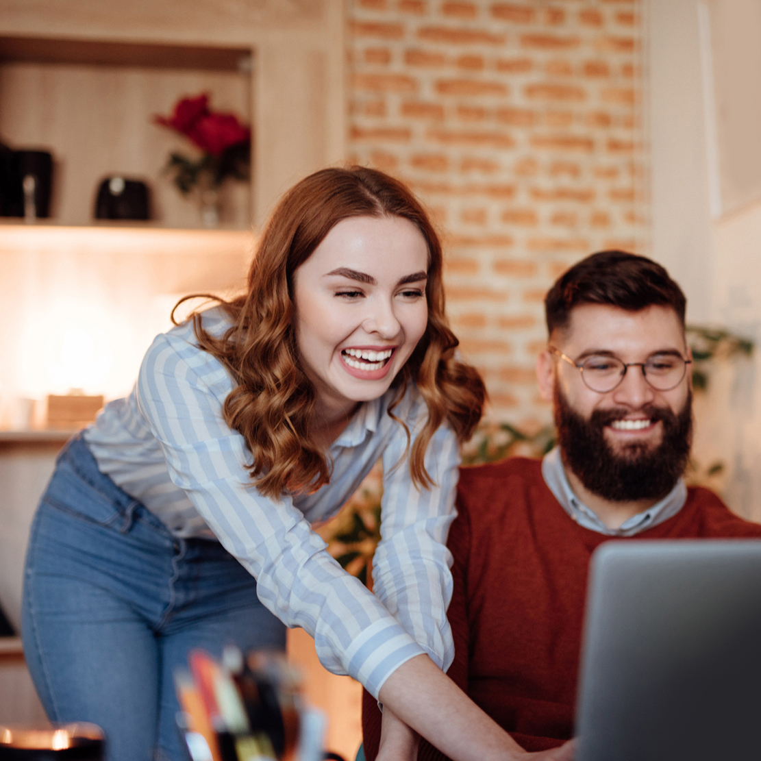 woman and man working together on their budget strategy she's pointing over his shoulder at their laptop