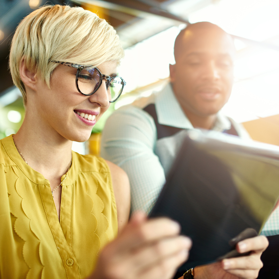 young woman holding an ipad showing her colleague the screen