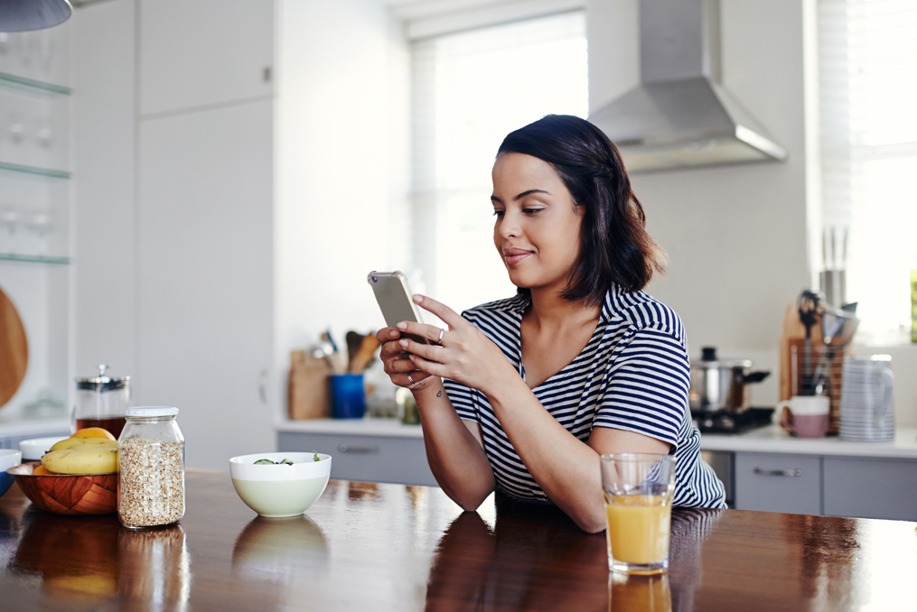 woman standing at her kitchen counter getting ready to make a phone call