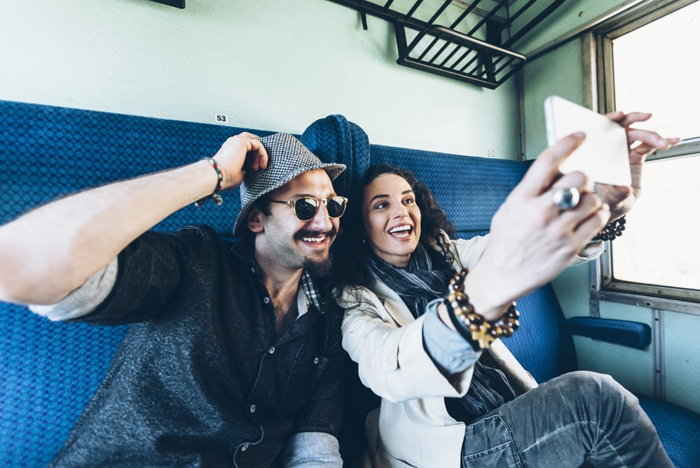 woman taking a selfie with her new partner while travelling on a train_how to avoid a sweetheart scam