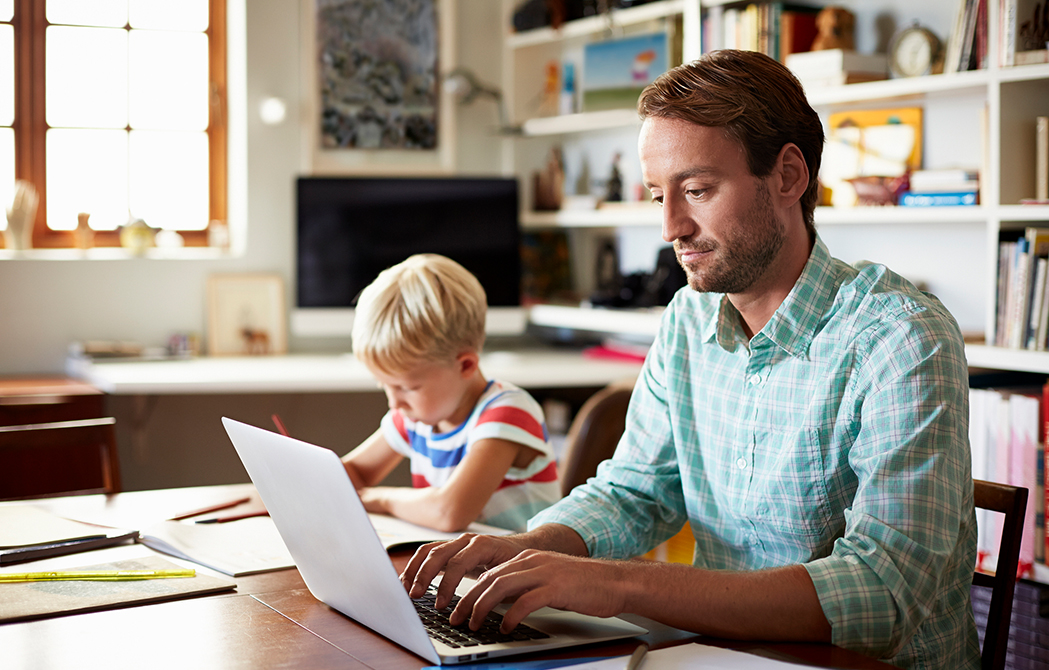 How to Implement Personal Cybersecurity Measures When You Work From Home_Man working from home next to son studying for school