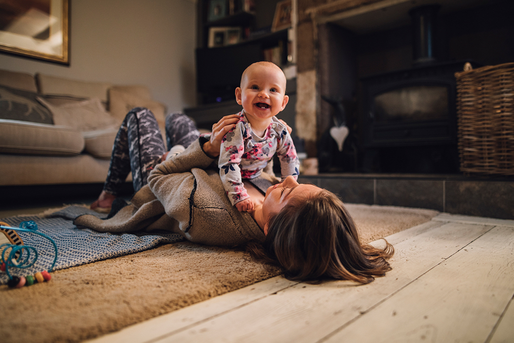 baby laughing while laying with mom on the floor