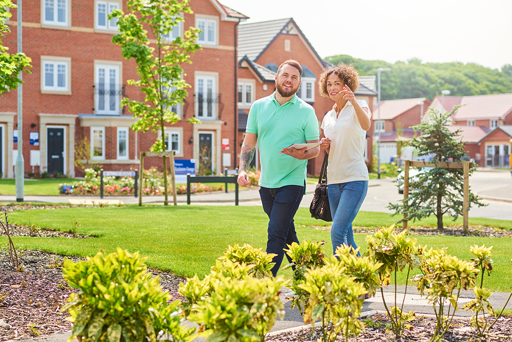 couple walking through a neighborhood on a sunny day house shopping