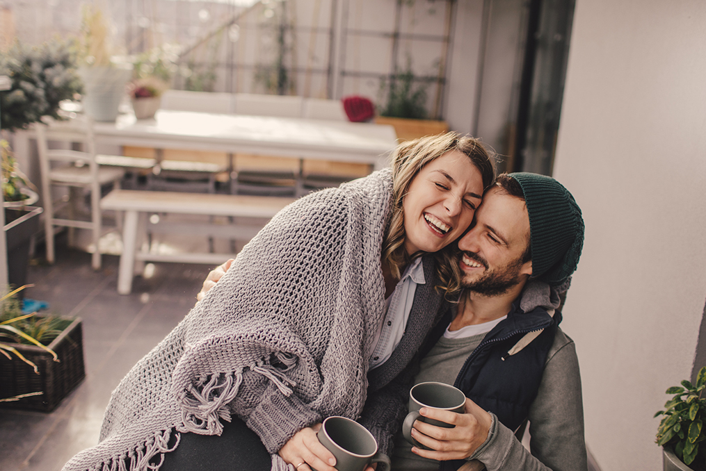 couple warming up with blankets and coffee at home