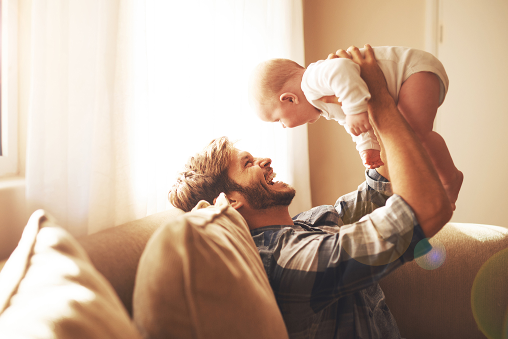 father holding baby while they both laugh