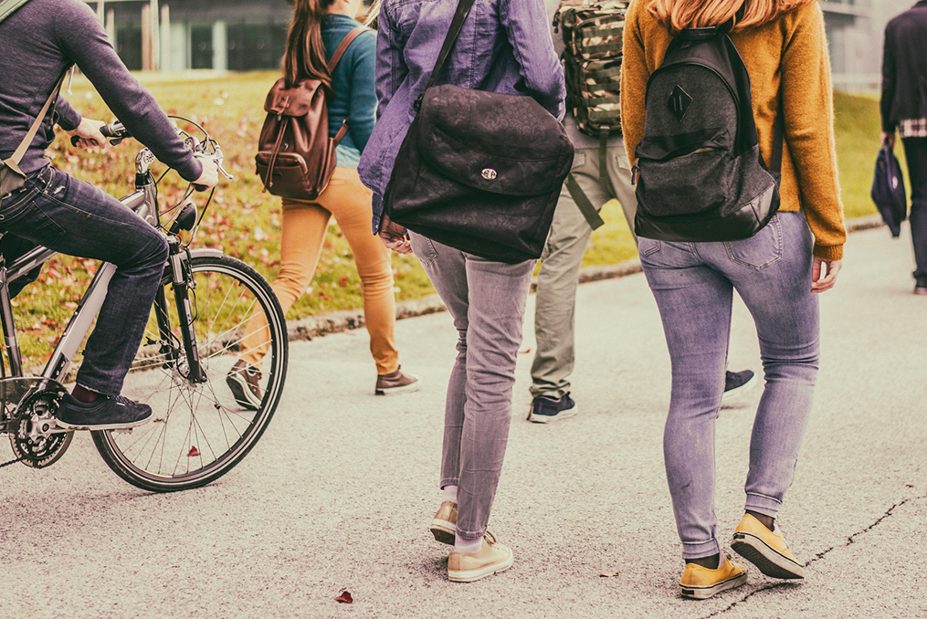 group of students walking and biking through a college campus