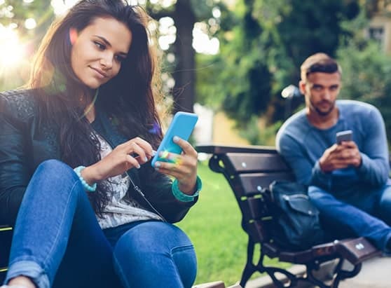 how-to-avoid-getting-trapped-in-a-sweetheart-scam_man-looks-over-womans-shoulder-in-the-park